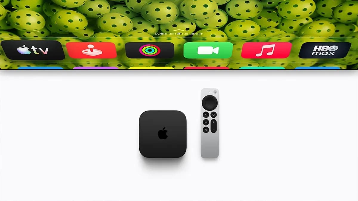 The black Apple TV 4K streaming box sitting on a wooden credenza alongside the aluminum Siri Remote.